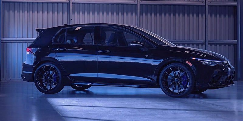 Side view of a dark blue hatchback with subtle blue lighting, parked in a concrete garage.
