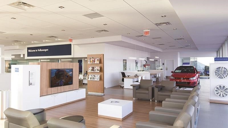 The waiting area of a modern Volkswagen dealership with a red car on display.